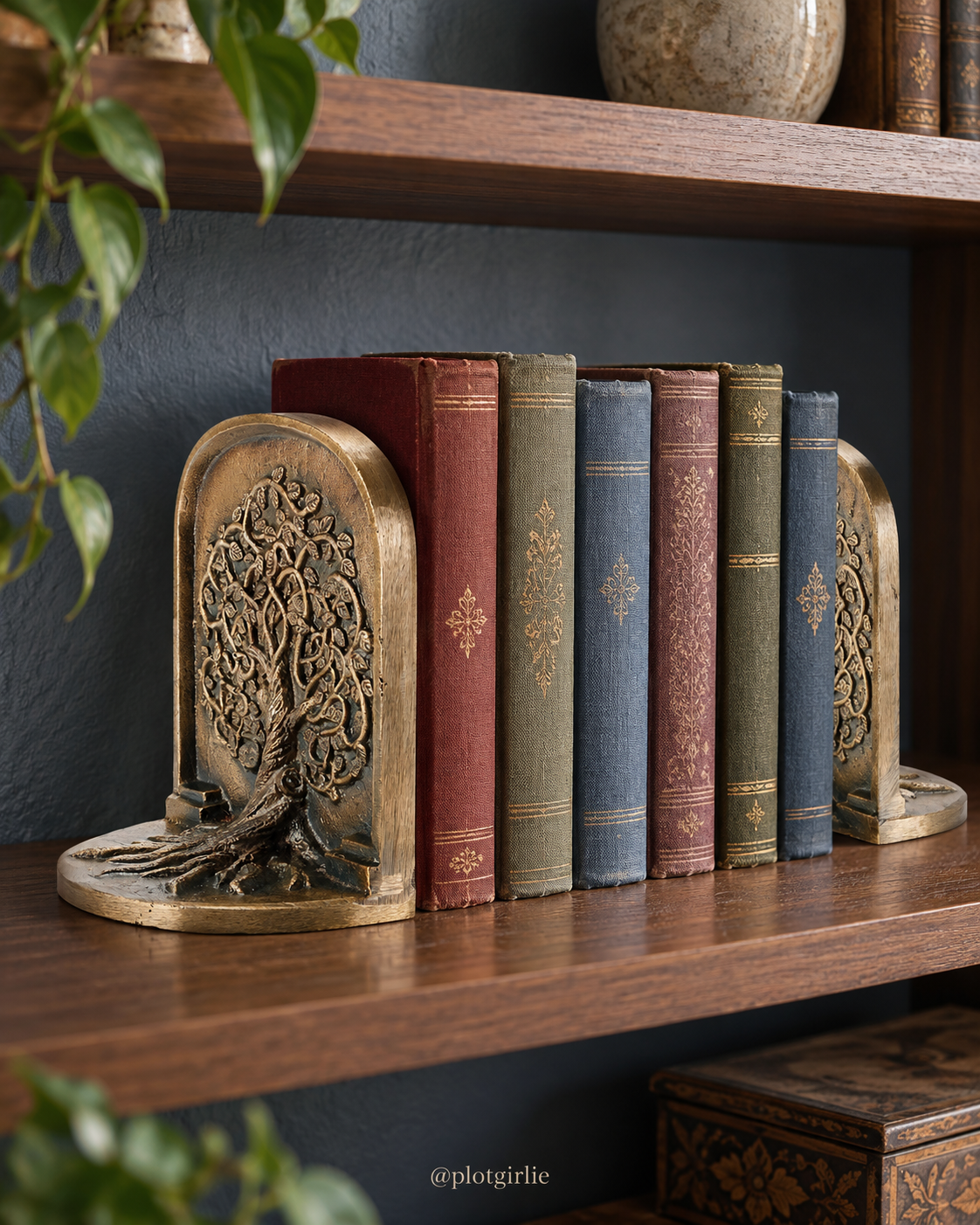 Antique-brass-style arched Tree of Life bookends with raised tree relief and spreading roots beside clothbound books